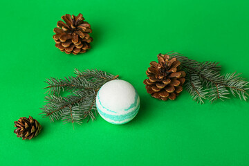 Bath bomb, pine cones and fir branches on green background
