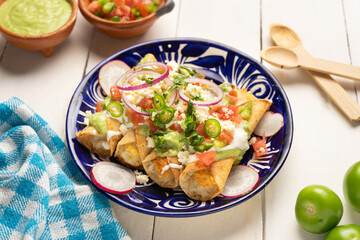 Mexican fried potato tacos called flautas with guacamole and cheese
