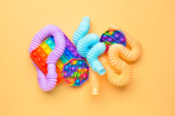 Colorful Pop Tubes and Pop it fidget toys on beige background - obrazy, fototapety, plakaty