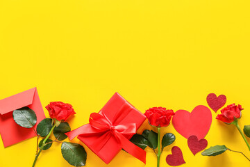 Composition with gift box, envelope and rose flowers on yellow background. Valentine's Day celebration