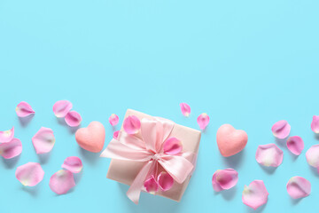 Composition with gift box for Valentine's Day, rose petals and hearts on color background