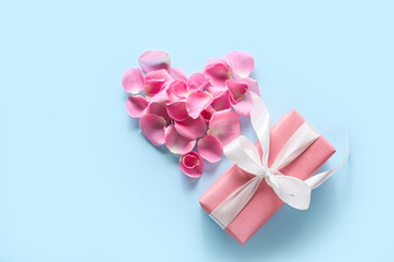 Heart made of rose petals and gift box on color background. Valentine's Day celebration