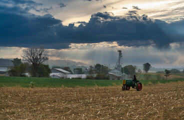 Obraz premium An Antique Farm Tractor Sitting in a Harvested Field Waiting, With a Person Looking Away