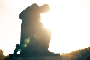 silhouette of a statue of a kneeing soviet soldier in the sun