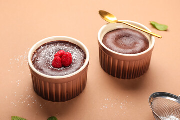 Ramekins with tasty lava cake fondant and raspberry on color background
