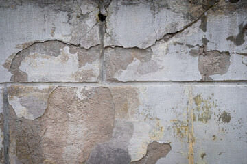 Damaged wall with holes texture background. Creative backdrop. Old, abandoned building interior fragment. Weathered and cracked bricks with concrete, peeled off paint and moss. Close up, copy space