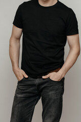 Obraz premium brutal attractive man poses in a black empty T-shirt made of thin premium cotton, highlighted on a white mock-up