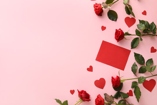 Composition with blank card, paper hearts and rose flowers on color background. Valentine's Day celebration