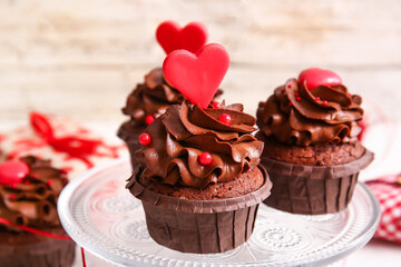 Stand with tasty chocolate cupcakes for Valentine's day on light table, closeup