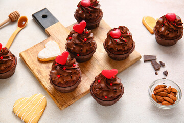 Board with tasty chocolate cupcakes for Valentine's day on light background