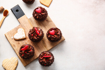 Board with tasty chocolate cupcakes for Valentine's day on light background