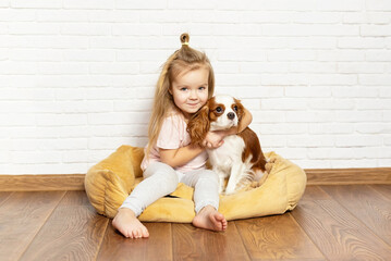 Obraz na płótnie Canvas Adorable little girl with puppy playing at home. Child with little dog indoor. The best and friendliest pet for kids and families, love for pet, love for dogs, special relationship with the pet.