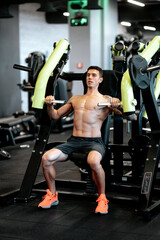 Fototapeta na wymiar Athletic shirtless young sports man - fitness model working out chest muscles at gym