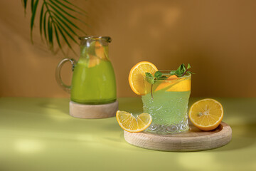 Glasses with lemonade or mojito cocktail with lemon orange and mint a cold refreshing drink on a color background
