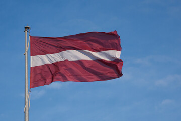 Fototapeta na wymiar Flag of the Republic of Latvia. Flag of Latvia against the blue sky. Copy space.