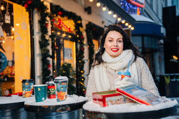 Charming woman with a smile on her face with a hot drink in her hands in winter on New Year's Eve