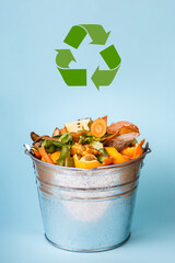 Compost-container front view. Sorted kitchen waste in compost-bucket on blue background. Sustainable lifestyle. Vegetable, fruit peels, scrap from food preparation collected in trash-can for recycling - 480268533