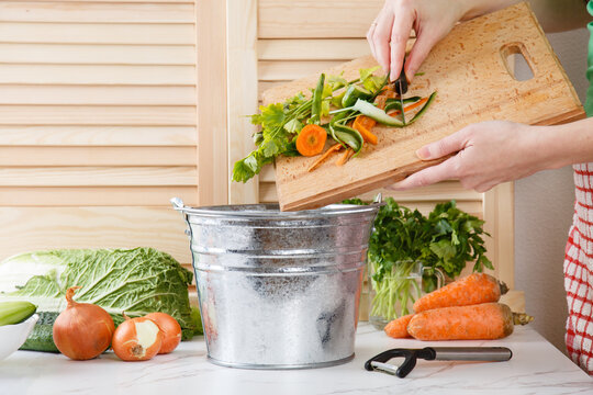 Sorting of household waste, composting. Collecting of food waste in trash-can for recycling. Woman throws vegetable peeling, scraps in compost bucket. Food waste reduce. Zero waste lifestyle. 