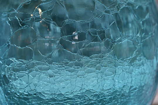 Close up of aqua blue glass sphere with crackle pattern.
