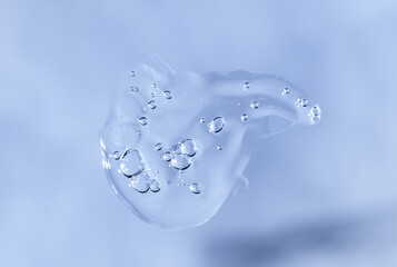 Drop of Fluid hyaluronic acid on blue. Cosmetics and healthcare concept closeup. Dose of serum or...