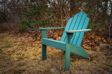 Green empty wooden bench. Cape Cod Adirondack chair in the autumn yard