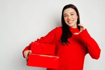 Attractive girl is smiling and looking straight at the camera. The girl is standing against the white background and holding gifts in the right hand. Concept of the St. Valentine's Day