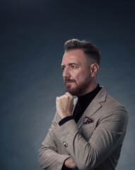 Obraz premium Portrait of a stylish elegant senior businessman with a beard and casual business clothes in photo studio isolated on dark background gesturing with hands