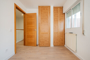 Bedroom with cherry-colored fitted wardrobes and Venetian doors and white aluminum radiator