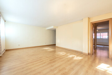Large empty living room with entrance to a bedroom with light oak hardwood flooring
