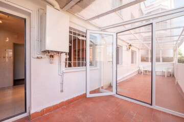 Enclosed terrace with white aluminum and glass structure and clay tile floors