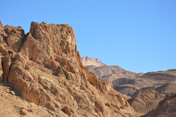 Atlas mountains near the Chebika oasis in west Tunisia, Africa. Whie, yellow, orange and brown rocks and blue sky.