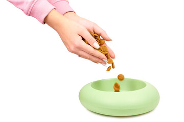 Close-up woman pouring with hands dry dog food into a bowl isolated on white background