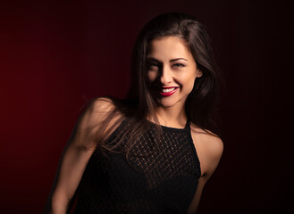 Beautiful happy laughing woman with red lipstick with bright makeup on dark red background with empty copy space. Closeup