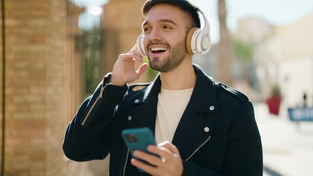 Young hispanic man smiling confident listening to music at street
