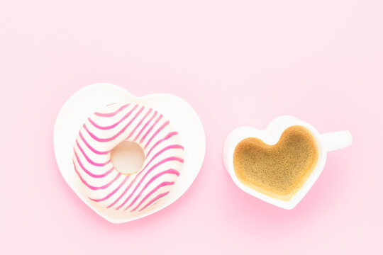 Coffee cup and pink donut in heart shape plate. Valentines Day concept. Top view, copy space.