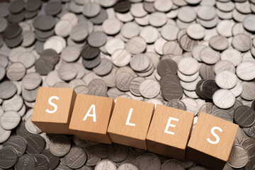 「SALES」と書かれた積み木とコイン