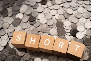 「SHORT」と書かれた積み木とコイン