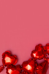 Foil balloons in the shape of a heart on a red background. Copy space. Festive vertical background for Valentines Day