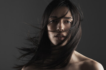 Fototapeta premium beauty fashion studio portrait of a beautiful young girl with windy hair in front of her face.