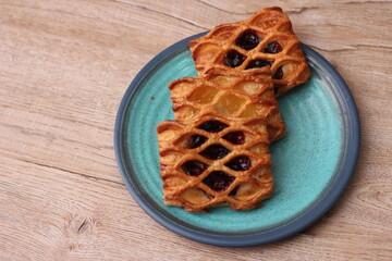 Lattice Jam Tart served in a plate on a wooden table.