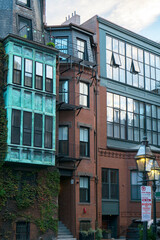 Historic brownstone houses with big windows and copper teal wall in Boston, Massachusetts. Climbing ivy plant on the wall