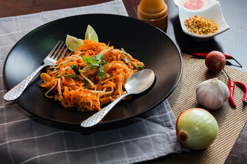 Thai Food Pad Thai (Thai national dish) Pad Thai on black plate with lime and seasonings.