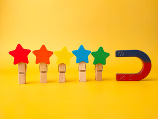 Colored wooden star attract by magnet on a yellow background.
