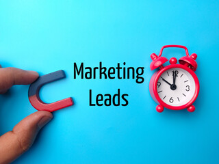 Hand holding magnet and clock with text Marketing Leads on blue background.