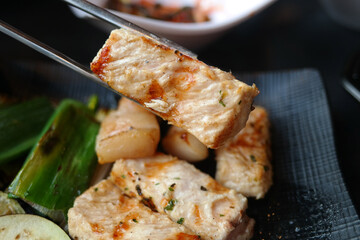 holding a thick pork chop with chopsticks.