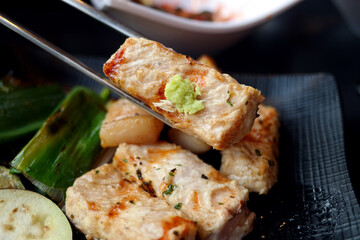 holding a thick pork chop with chopsticks.