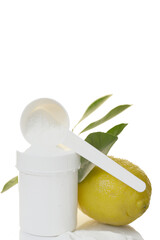 Vitamin C powder, white measuring spoon, white jar and lemon in a cut with green leaves isolated on...