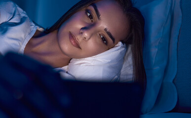 Woman using smartphone in bed with before sleep