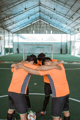 group of male futsal players standing in a circle praying