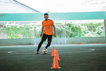 a male futsal player practicing dribbling on an indoor court